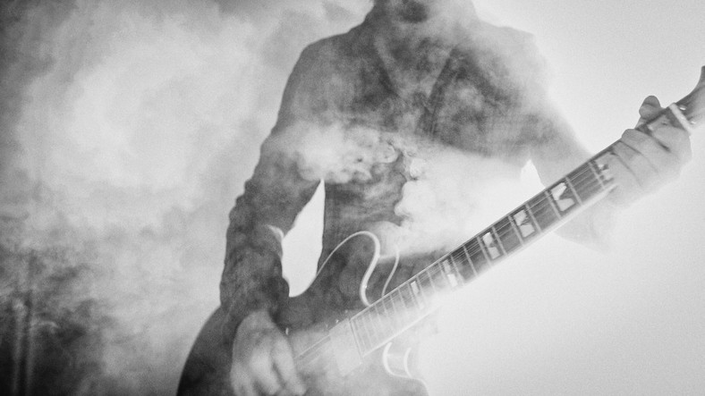 Man playing a guitar surrounded by smoke